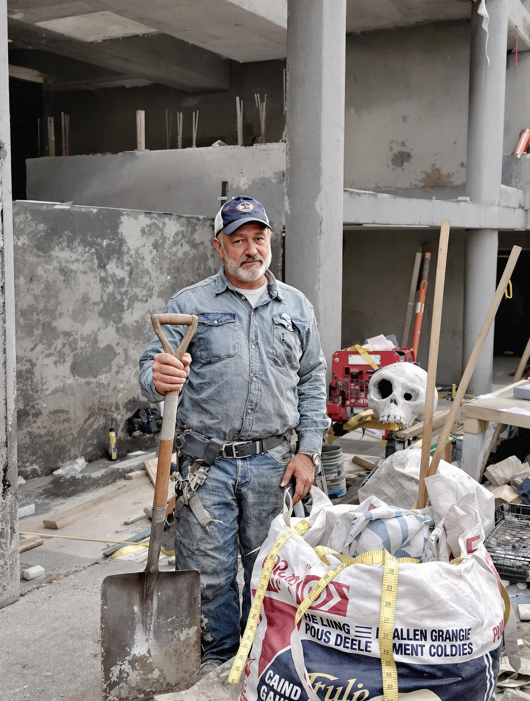 Bricoleur un peu blasé tenant une pelle sur un chantier bétonné