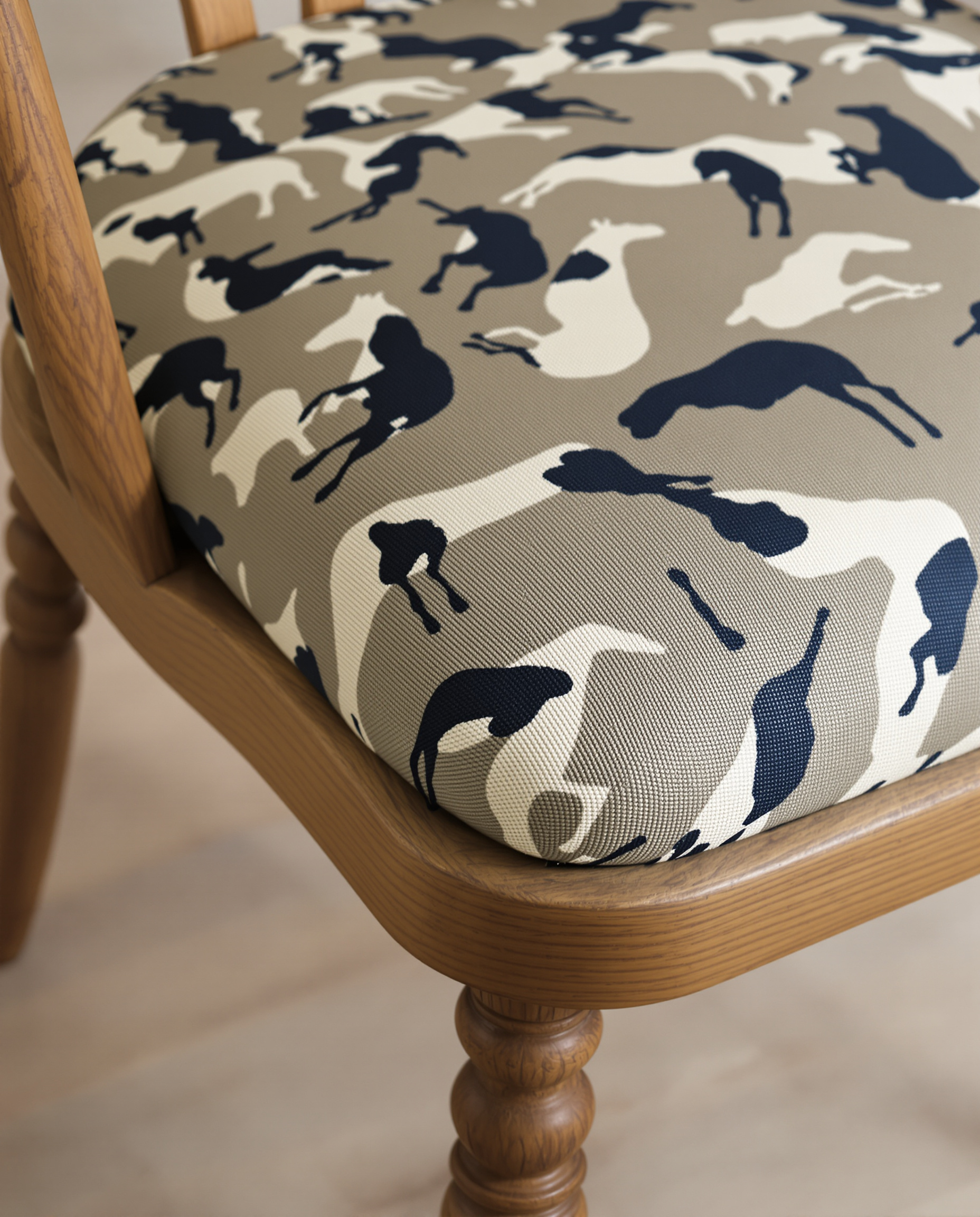 Gros plan sur l'assise d'une chaise en bois vintage, recouverte d'un tissu à motif cheval graphique et moderne, illustrant une customisation réussie et originale.