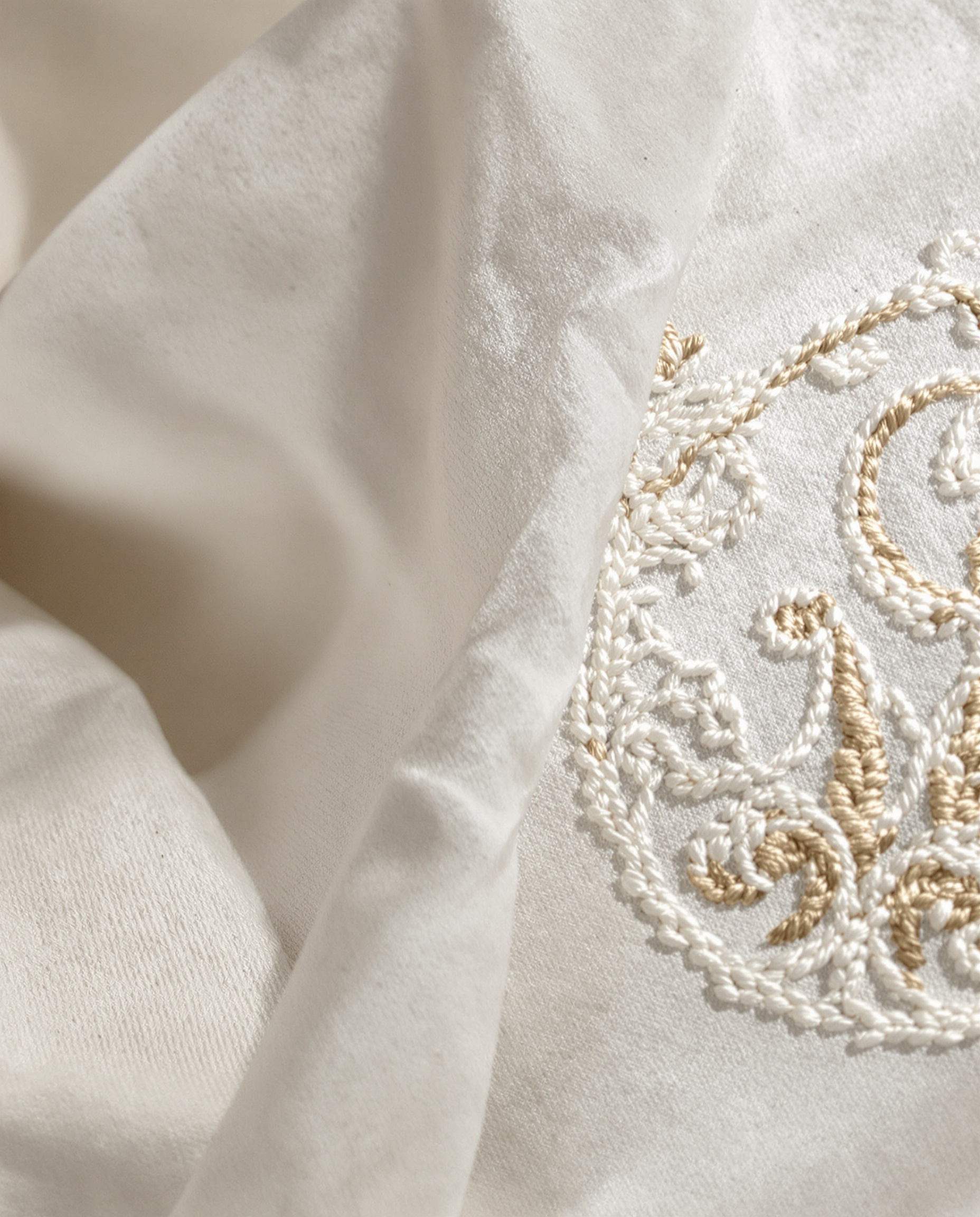 Gros plan sur la texture d'un drap en lin ancien avec détail de monogramme brodé.