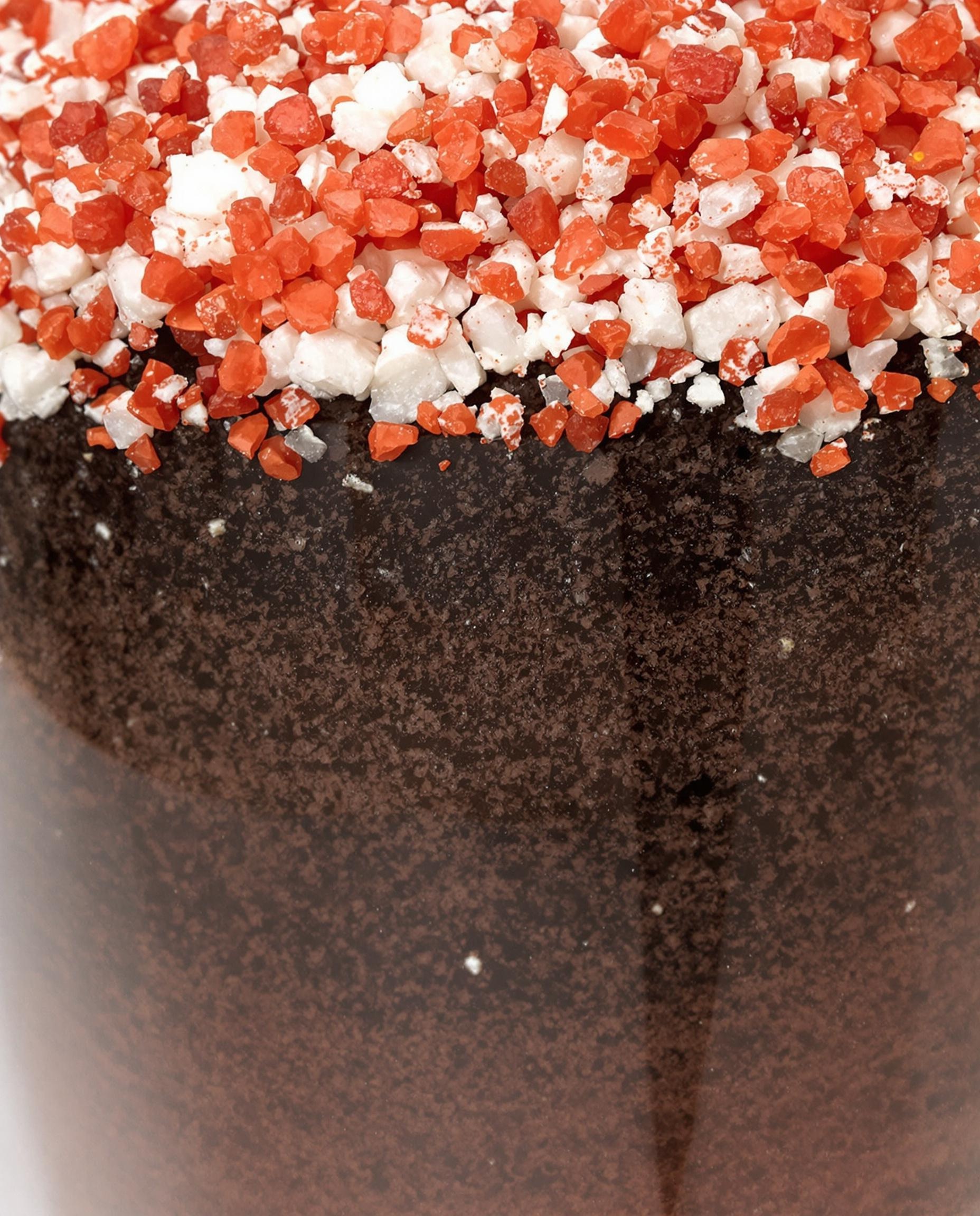 Zoom sur un substrat aéré avec granules de pouzzolane rouges, perlite blanche et terreau brun sombre.